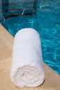 One rolled-up white towel by blue pool