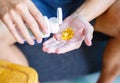 Close up photo of one round yellow pill in hand. Man takes medicines with glass of water. Daily norm of vitamins, effective drugs, Royalty Free Stock Photo