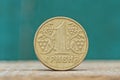 One round yellow Ukrainian hryvnia coin on a gray table on a green background Royalty Free Stock Photo