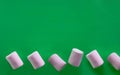 one row of pink and white marshmallows on a green background, space for text