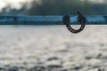 One rusty horseshoe hanging on a metal pasture gate on a sunny winter morning. Symbol of good luck, lucky charm in equestrian