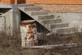 Rusty old barrel stands in dry grass near the house with a ladder Royalty Free Stock Photo