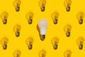 One saving light bulb and many incandescent lamps on a yellow background. Idea concept Royalty Free Stock Photo