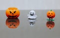 One scary orange pumpkin shaped candle, plastic white ghost toy and orange funny smiling pumpkin toy with green legs, isolated on Royalty Free Stock Photo