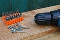 One screwdriver with a set of bits in a plastic box in a pile of screws on a wooden table Royalty Free Stock Photo