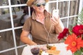 One senior people at the table tasting some appetizer and talking on the phone. Break on the terrace for the elderly caucasian