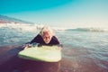 One senior trying surfing alone in the water of the beach and learning surf - mature old man waiting for the waves with his long