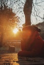 One serene woman having relax sitting at the bench at the park in autumn sunset day time. Winter warm jacket. Happy thoughtful Royalty Free Stock Photo