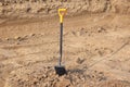 One shovel with bright yellow handle stuck to the ground. Ground works, excavations.