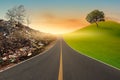 One side of the road shows the green tree on green mountains, and the other side shows dead trees on mountains of trash