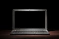 One silver modern laptop on wooden table in a dark room on black background. Nice mockup for your IT project. Dramatic light.