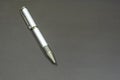 One silver office pen lies on a black matte surface. Ballpoint pen on the table on the left Royalty Free Stock Photo