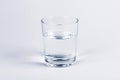 One simple half full half empty glass of fresh crystal clear clean drinking water, solo object isolated on light blue background Royalty Free Stock Photo