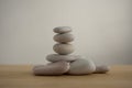 One simplicity stones cairn isolated on white background, group of light gray pebbles built in tower, wood table Royalty Free Stock Photo