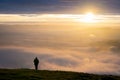 One single anonymous man standing on mountain alone watching sunrise silhouetted stood high above the clouds Royalty Free Stock Photo