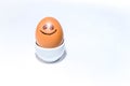 One single brown egg with positive face smiling stands in an egg holder on white backdrop. Drawn black smile