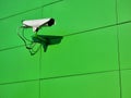 One single CCTV live video surveillance camera on a green wall, closeup, copy space. Urban safety and security equipment, city Royalty Free Stock Photo