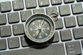 One single compass laying on a modern computer desktop PC keyboard, world navigation, different directions, NSWE object closeup,