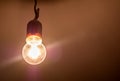 One single old plain bright incandescent lightbulb on in a darkened room, object detail, closeup, from below Bright yellow light