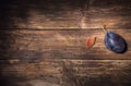 One single plum and a plum stone on a dark wooden board. Fruit background. Text space. Top view. Agriculture, Gardening, Harvest