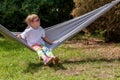 One single school age child, girl wearing cool sunglasses sitting on a hammock, resting in the sun summer leisure activities Royalty Free Stock Photo