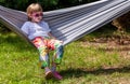 One single school age girl, child in sunglasses and colorful clothes sitting resting on a hammock outside, outdoors, backyard Royalty Free Stock Photo