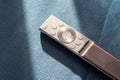 One single simple silver premium smart TV remote control laying on a sofa, couch, object in the sun, detail, closeup, nobody Royalty Free Stock Photo