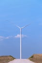 One single windmill turbine in front of road with blue sky in background. Renewable energy wind turbine Royalty Free Stock Photo