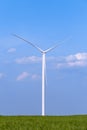 One single windmill turbine on green agricultural field with blue sky in background. Renewable energy wind turbine Royalty Free Stock Photo