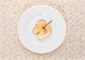 One slice of dried apple on white plate on beige ornate patterned background