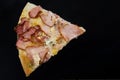 One slice of pizza on a black background. Pizza with cheese and ham. Close-up. Copy space. Royalty Free Stock Photo