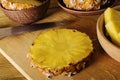 Pineapple and knife sits on a wood chopping board on wooden background