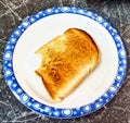One slice of toast had bite marks.The word is on a white plate with a blue patterned edge. Royalty Free Stock Photo