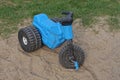 One small blue black plastic childrens tricycle stands on gray sand