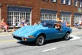 One small blue car driving on the road in the fourth of July parade