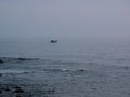 One small fishing boat heading out on the foggy ocean at dawn