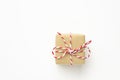 One small gift box wrapped in brown craft paper tied with striped red ribbon on white background. Christmas New Year presents