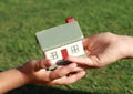 One small kids hand giving a model of a house