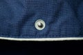 One small metal button rivet on blue fabric