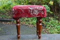 One small ottoman chair with a soft seat made of red fabric and brown wooden legs Royalty Free Stock Photo