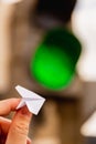 One small paper airplane in hand against a traffic light background with a glowing green signal. Permission to fly. Takeoff