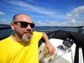 One smiling bearded adult man sailing on a sailboat during his yacht voyage in a sunny summer day