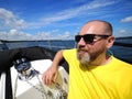 One smiling bearded adult man sailing on a sailboat during his yacht voyage in a sunny summer day