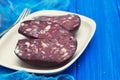 Smoked sausage morsela on white dish on wooden background Royalty Free Stock Photo