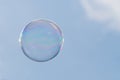 One soap bubble floating against light blue sky. 