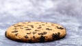 One soft, freshly baked chocolate chip cookie on a gray marble kitchen countertop. American traditional dessert. Delicious sweet