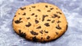 One soft, freshly baked chocolate chip cookie on a gray marble kitchen countertop. American traditional dessert. Delicious sweet