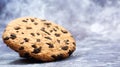 One soft, freshly baked chocolate chip cookie on a gray marble kitchen countertop. American traditional dessert. Delicious sweet