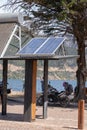 One solar panel in a pole in the middle of a park with a lake and trees around it Royalty Free Stock Photo