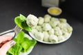 One spinach gnocchi on the fork in woman hand and many on the ba